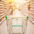 Einkaufswagen der in einem Supermarktgang mit Regalen steht