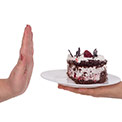 Eine Hand hält einen Teller mit einem Stück Torte, die andere Hand lehnt den Teller ab