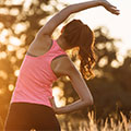 Frau in rosa Sport Top mit einer Hand oben macht Dehnübungen Rückenansicht