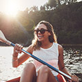 Junge Frau sitzt in einem Kanu mit einem doppelseitigen Paddel in den Händen