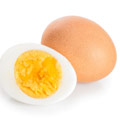 Ein gekochtes halb aufgeschnittenes Ei mit ganzem Ei dahinter liegend auf weißem Hintergrund