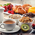 Leckeres Frühstück mit Müsli, Kaffee, Obst und Gebäck auf hölzernem Untergrund