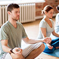 Mann und Frau in Yogastudio die in der Schneidersitzposition verweilen