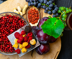 Himbeeren, Pflaumen, Goji, Cranberries und Trauben auf einem Tisch