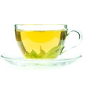 Durchsichtige Teetasse mit grünem Tee gefüllt auf weißem Hintergrund