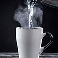 Weiße Tasse in die von oben heißes Wasser eingefüllt wird